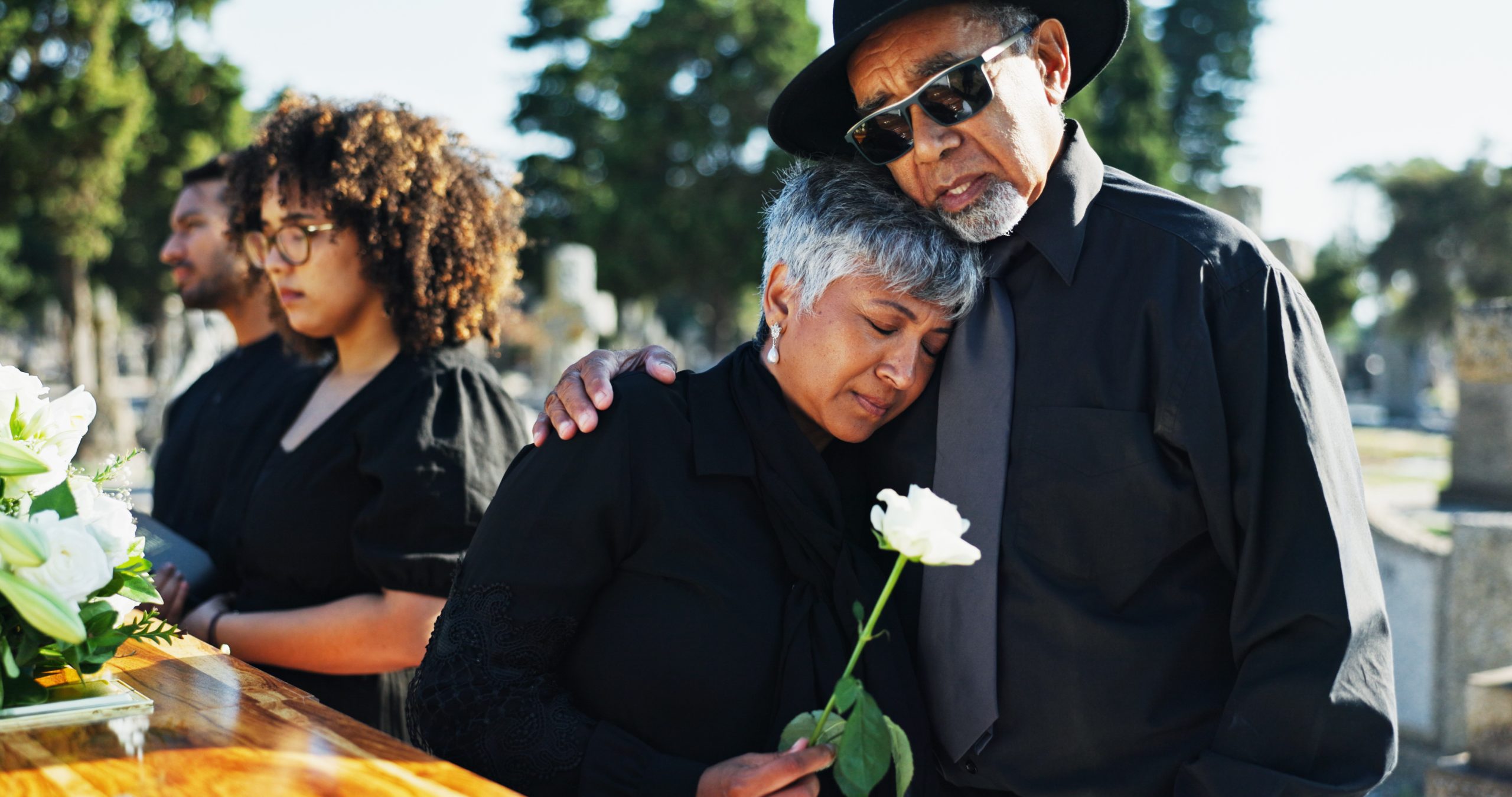 Embrace, sad and funeral with people, graveyard and grief with emotion, empathy and  sorrow. Ceremony, outdoor or family with loss, support or comfort with compassion, mourning or burial for death.