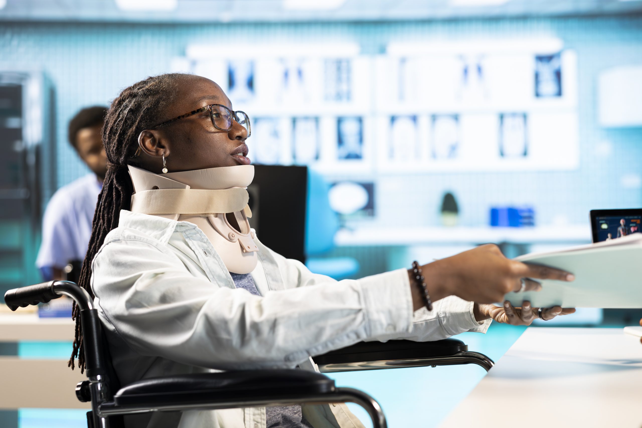 Wheelchair user with a fractured neck injury wearing cervical foam collar, talking to specialist about painkillers or advice for recovery. Young girl with spinal fracture at checkup.